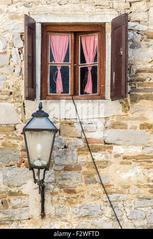 ein schönes Fenster mit offenen braunen hölzernen Fensterläden und Vorhänge Stockfoto