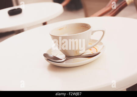 Schmutzige Kaffeetasse und Untertasse in einem Café draußen auf einem Tisch Stockfoto