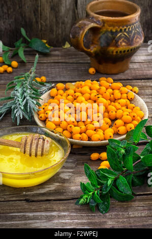 Reifen Beeren des Sanddorn in Untertasse auf hölzernen Hintergrund Stockfoto