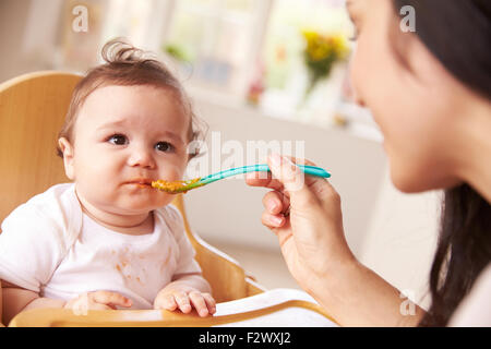 Happy Baby gefüttert In Hochstuhl zu den Mahlzeiten Stockfoto