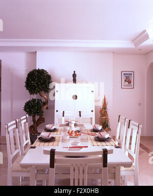 Weiss lackiert, Stühle und Tisch für das Mittagessen im modernen weißen spanischen Speisesaal mit einer kleinen Wolke beschnittene Baum Stockfoto