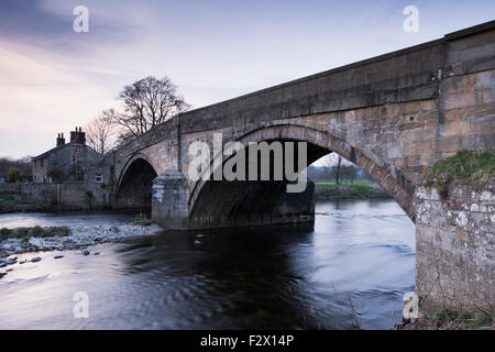 Malerische Aussicht bei Sonnenuntergang, traditionellen, alten, Stein, Straße Brücke über fliessendes Wasser des Flusses Wharfe in der Nähe von Bolton Abbey, Yorkshire Dales, England, UK. Stockfoto