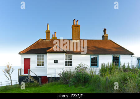 Alt weiß lackiert Holzhaus mit roten Eingangstür und gefliesten Dach in der Nähe von Cuckmere Haven an der Küste von Sussex im Süden Englands Stockfoto