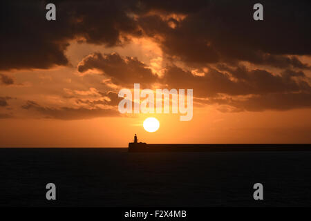 Der Leuchtturm am Hafen Newhaven an der Küste von Sussex im Süden Englands, in der Silhouette bei Sonnenuntergang. Stockfoto