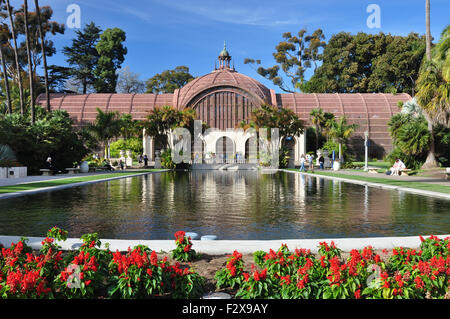 Rote Blumen Rahmen dieser Blick auf den botanischen Gebäude und den Teich im Balboa Park in San Diego, Kalifornien. Stockfoto