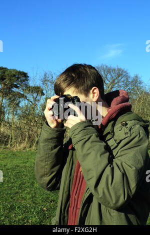 15-jähriger Junge, Foto mit 35mm Film Kamera im Feld im Winter bei Brabourne Lees, Ashford, Kent, England Stockfoto