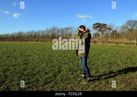 15-jähriger Junge, Foto mit 35mm Film Kamera im Feld im Winter bei Brabourne Lees, Ashford, Kent, England Stockfoto