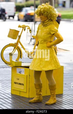 Frau in Gelb mit einem Fahrrad Straßenmusik auf der Straße von Barcelona Stockfoto