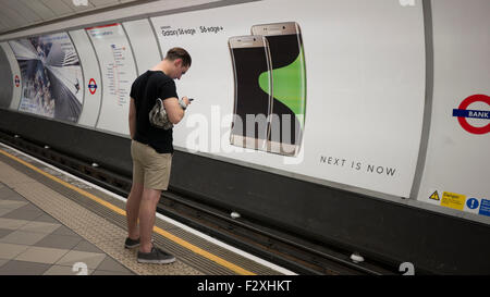 Männlichen Blick auf Handy vor Werbung Horten Plakat am Londoner u-Bahn Anzeigen Samsung Galaxy S6 Kante Stockfoto