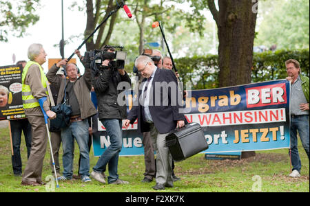 Berlin, Deutschland. 25. Sep 2015. Rainer Bretschneider, Staatssekretär und Brandenburg Zustand Flughafenkoordinator, kommt nach einer Aufsichtsratssitzung des Flughafens Berlin Brandenburg tätiges Unternehmen, als Demonstranten ein transparent halten, die liest "Milliardengrab BER - Stoppt Den Wahnsinn - Neuer Standort Jetzt!" (lit.) Sinkende Milliarden in BER [als IATA-Code] - stoppt den Wahnsinn! -Neuer Standort jetzt!) in Berlin, Deutschland, 25. September 2015. Foto: KLAUS-DIETMAR GABBERT/Dpa/Alamy Live News Stockfoto