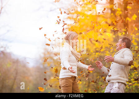 Aktive Senioren Spaß haben und spielen mit den Blättern im herbstlichen Wald Stockfoto