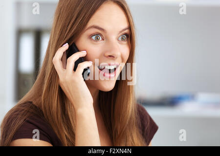 Porträt des jungen überrascht Business-Frau am Telefon sprechen. Stockfoto