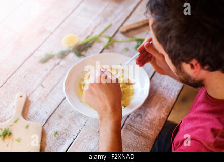 Schönen jungen Mann in der Küche essen Lachs tagliatelle Stockfoto