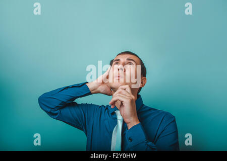 ein Mann der Europäischen Auftritt dreißig Jahren denken Hand am Kinn auf grauem Hintergrund Stockfoto