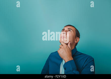 ein Mann der Europäischen Auftritt dreißig Jahren denken Hand am Kinn auf grauem Hintergrund Stockfoto