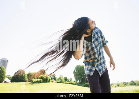 Ein junger Mann schüttelt den Kopf mit Hisl Ong Haar im Wind. Stockfoto