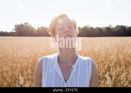 Kopf und Schultern Porträt einer jungen Frau, stehend in einem Maisfeld. Stockfoto