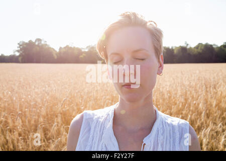 Kopf und Schultern Porträt einer jungen Frau, stehend in einem Maisfeld. Stockfoto