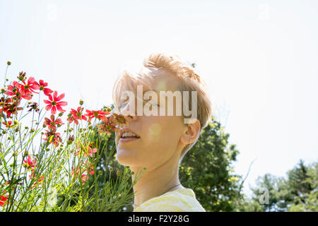 Eine junge Frau in eine Blume Grenze, Angesicht zu Angesicht mit Palette Rudbekia Blumen. Stockfoto