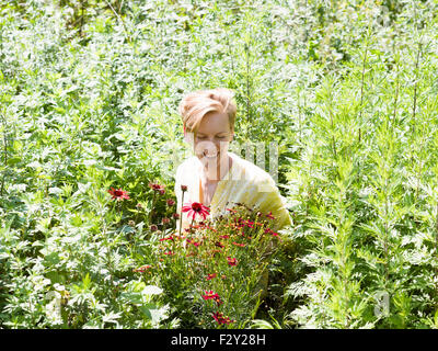 Eine junge Frau in einem Stauden Bett umgeben von Pflanzen und Blumen in einer Gärtnerei. Stockfoto