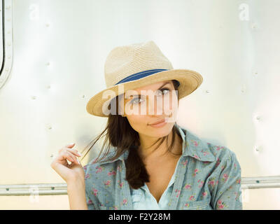 Eine junge Frau in einem Strohhut, ihr Kopf gekippt, schauen neugierig. Stockfoto