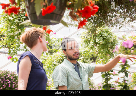 Ein Mann und eine Frau betrachten bunt blühende Pflanzen in einem Garten-Center. Stockfoto