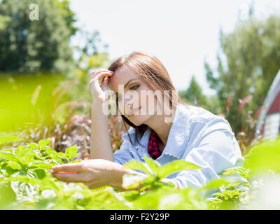 Eine junge Frau von Racks von Pflanzen in einem kommerziellen Kinderzimmer. Stockfoto