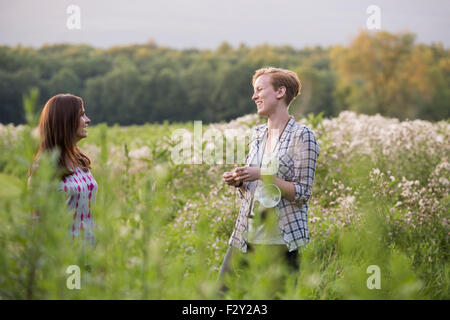 Zwei Frauen stehen auf einer Wiese, umgeben von hohe Gräser und Wildblumen. Stockfoto