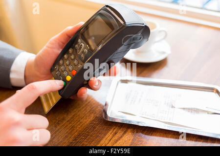 Hand des Mannes mit Kreditkarte Swipe über Terminal zu verkaufen, im Restaurant. Code-Tastatur Stockfoto