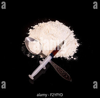 Droge-Pulver, Medikament Spritze und gekochte Droge auf Löffel Nahaufnahme auf einem schwarzen Hintergrund. Stockfoto