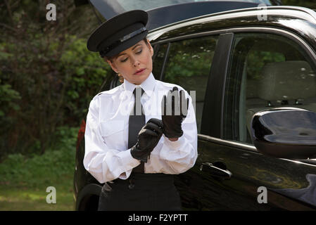 Frau Chauffeur trägt einen Hut und setzen auf ihre einheitliche schwarze Lederhandschuhe Stockfoto