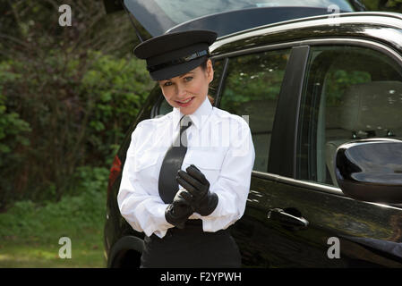 Frau Chauffeur trägt einen Hut und setzen auf ihre einheitliche schwarze Lederhandschuhe Stockfoto