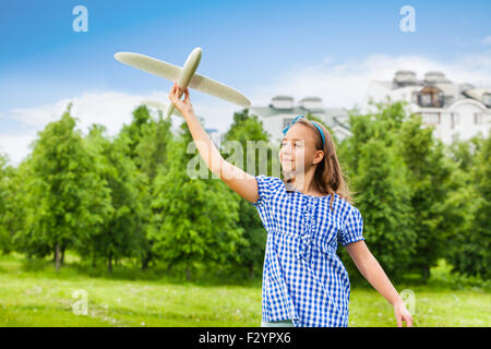 Glückliches Mädchen hält Flugzeug Spielzeug mit geraden arm Stockfoto