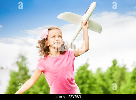 Glückliches Mädchen hält weißes Flugzeug Spielzeug mit arm Stockfoto