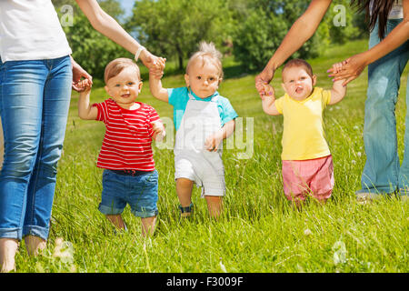 Glückliche Kleinkinder laufen lernen halten Mütter Hände Stockfoto