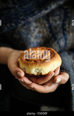 Frau halten, dass eine schwedische Kanelbullar Zimtschnecken Stockfoto