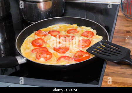 Spanisches Omelett mit Tomaten in der Pfanne gekocht wird. Stockfoto