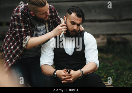 Barbier rasiert ein bärtigen Mannes Stockfoto