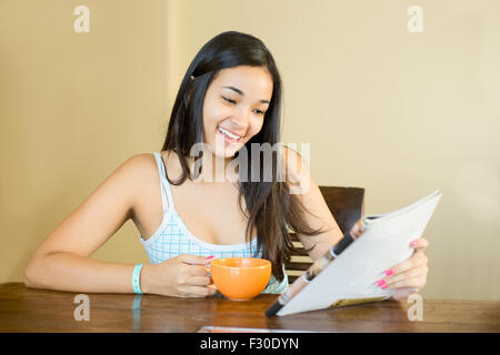 junge Frau liest eine Zeitschrift mit einem Kaffee Stockfoto