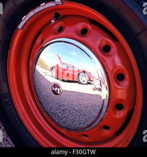 Ein roter Ferrari spiegelt sich in der Radkappe eines anderen Fahrzeugs, Gaydon, Warwickshire, England, Vereinigtes Königreich, West-Europa. Stockfoto