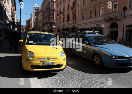 Ein gelber Fiat 500 Cinquecento mit der Nummer 5 auf der Motorhaube und Polizeiwagen, Via Nazionale, Roma, Rom, Italien. Stockfoto