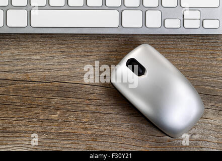 Selektiven Fokus auf drahtlose Computer-Maus mit teilweise Tastatur im Hintergrund. Layout im Querformat auf rustikalen Holz. Stockfoto