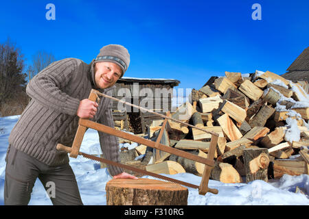 Mann mit Säge sammeln von Brennholz im Winter im freien Stockfoto