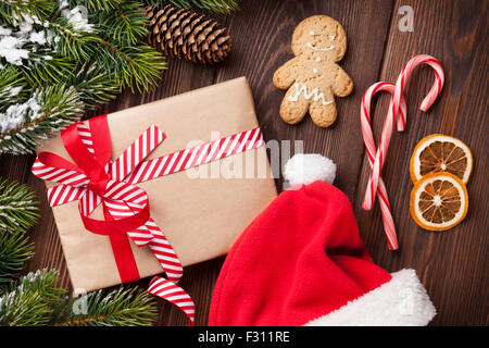 Weihnachten Baum über hölzerne Hintergrund mit Weihnachtsmütze, Lebkuchenmann und Geschenkbox Stockfoto