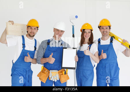 Gruppe von lächelnden Bauherren in Schutzhelme mit Werkzeugen im Innenbereich Stockfoto