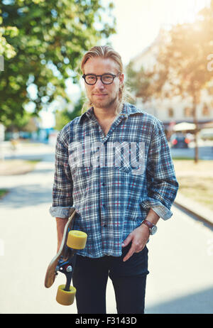 Porträt von cool junger Mann mit langen Haaren und Brille tragen eine skateboard Stockfoto