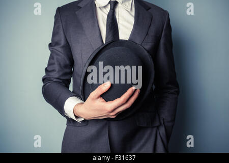 Junger Mann im Anzug hält eine Melone Stockfoto