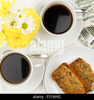 Kaffee und ein leckeres Stück von Gluten freie Datum und Walnuss Brot Kuchen, hübsches Tischgesteck. Stockfoto