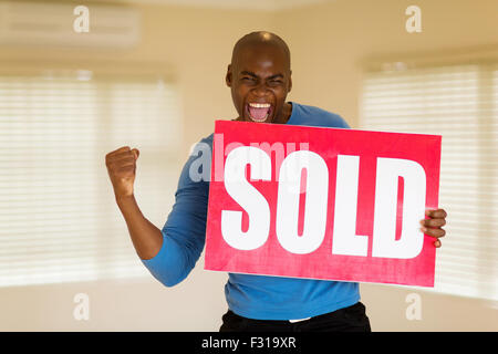 aufgeregt afrikanischen Mann Holding verkauft Zeichen in seinem Haus Stockfoto