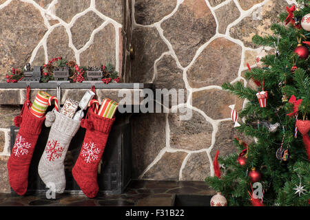 Strümpfe, die an einen Kamin neben einem Weihnachtsbaum hängen am Weihnachtsmorgen Stockfoto